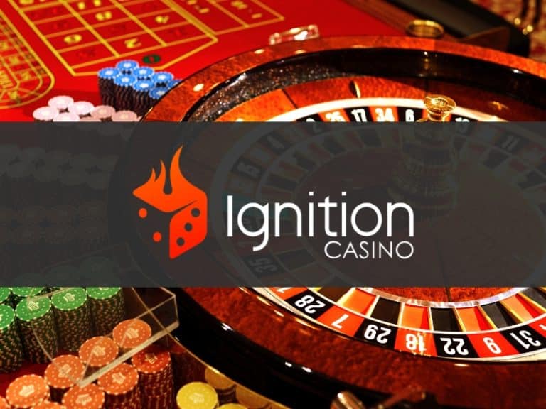 Betting chips and roulette wheel at casino table.